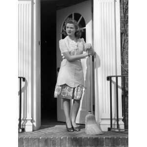  Woman Wearing Apron With Broom in Open Front Door 