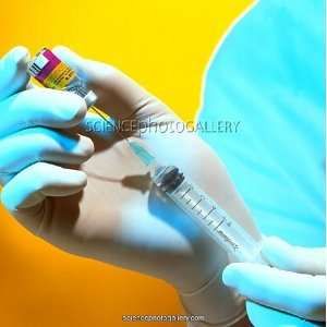  Gloved hand drawing MMR vaccine into a syringe Framed 
